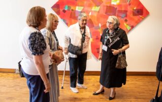 Artist and guests standing together, chatting at the art gallery opening event.