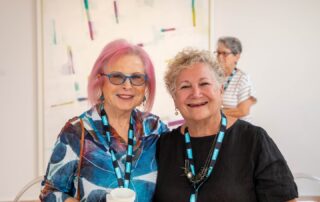 Two event attendees standing together, wearing name badges, enjoying the gallery talk and tour.
