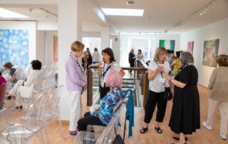 Visitors chatting in the bright gallery hallway surrounded by contemporary artwork.