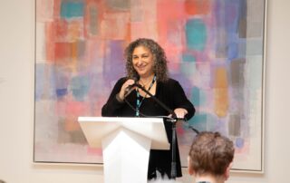 Speaker at the podium addressing guests at Baycrest’s art event.