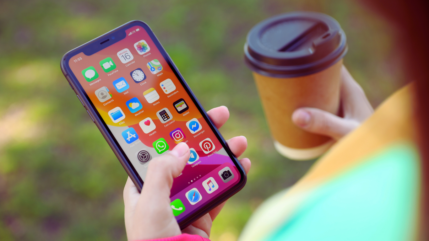 A person holding an iphone with different apps to help manage caregiving