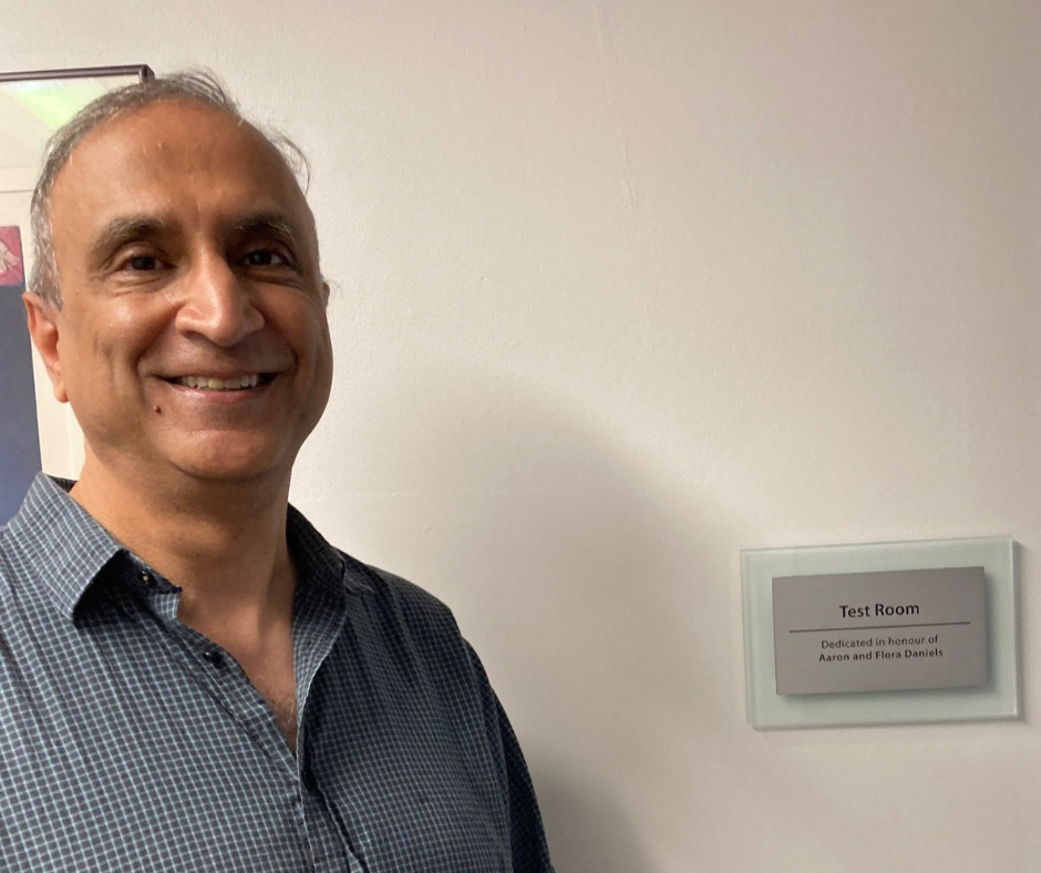 Doron Daniels standing in front of a Memory Link program room plaque in honour of his parents, for his thoughtful philanthropy